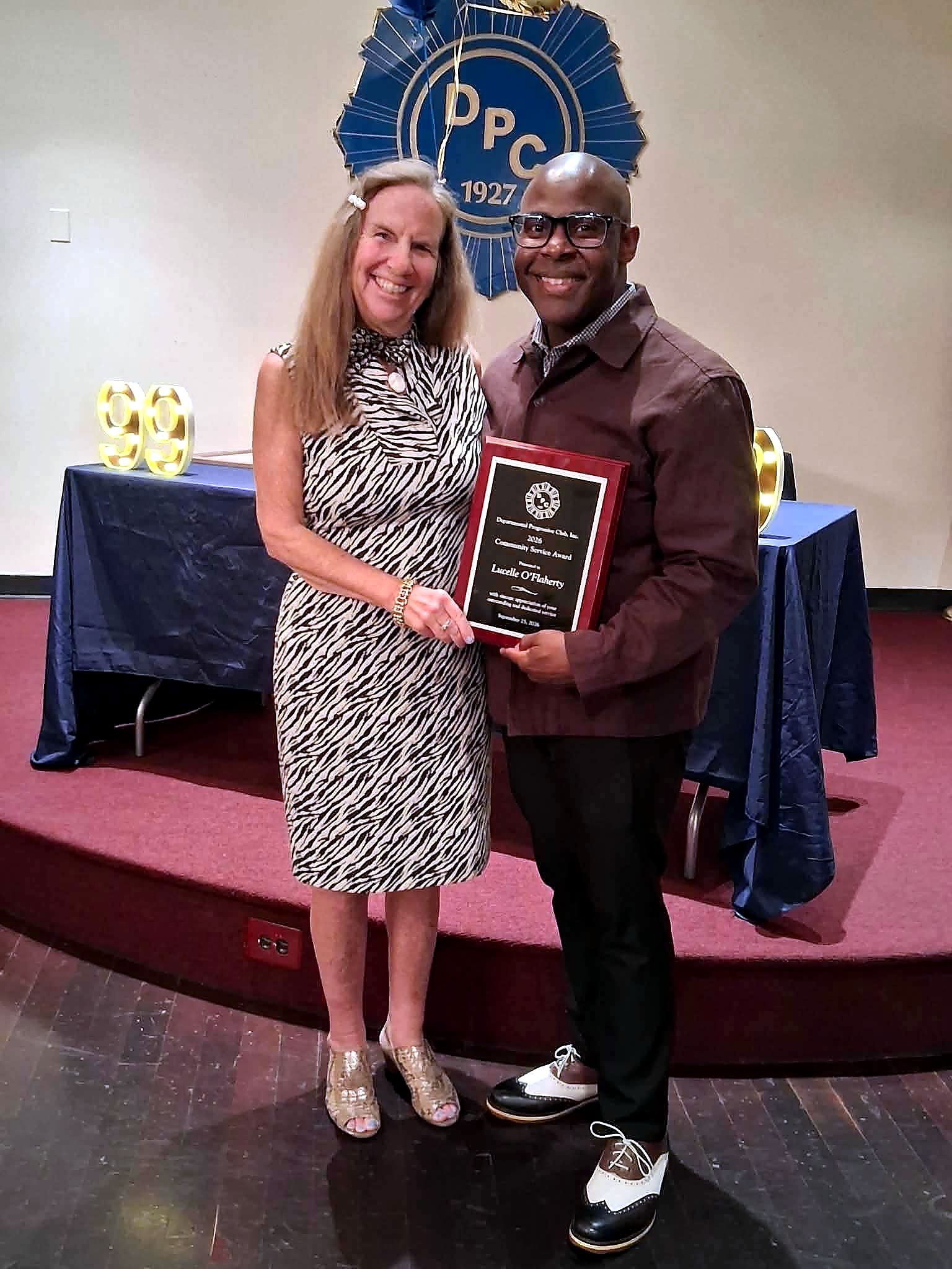 Lucelle O’Flaherty holds the Departmental Progressive Club Community Service Award with a DPC representative during the club’s 99th anniversary celebration.