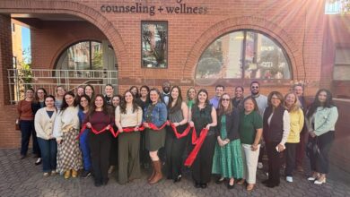 Ribbon-cutting attendees hold a red ribbon outside Wonderologie Counseling + Wellness on Mount Vernon Avenue.