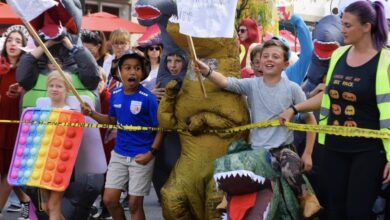 Children in dinosaur and rainbow pop-it costumes join participants at the 2023 Del Ray Halloween Parade.