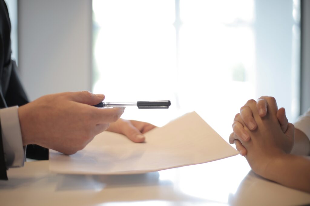 A stock image of someone being handed a document to sign, representing one of the three main types of contract under employment law in Mexico