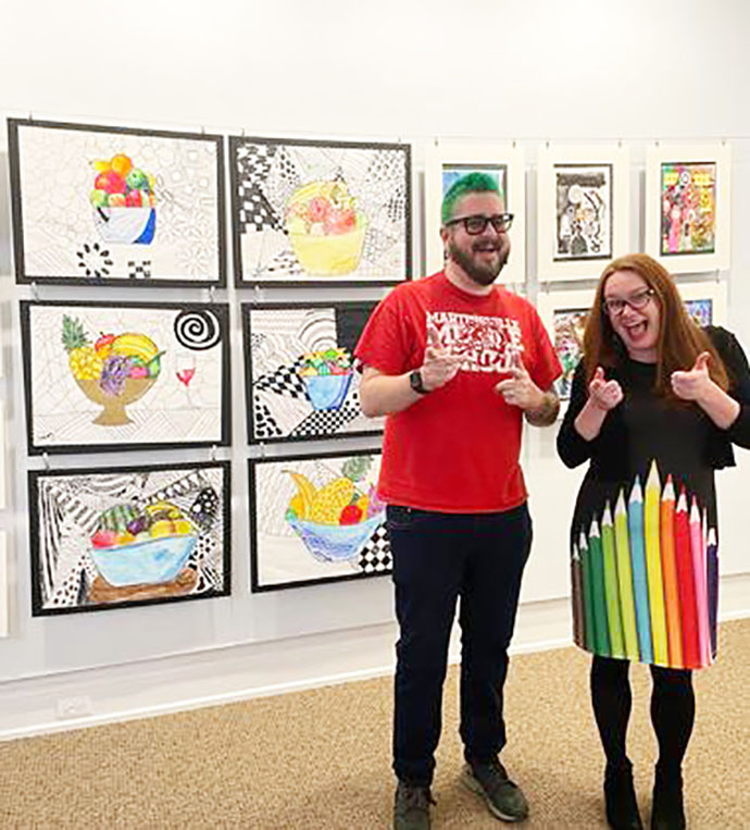 Proud teachers pose with their students’ creations in the Foster Gallery.