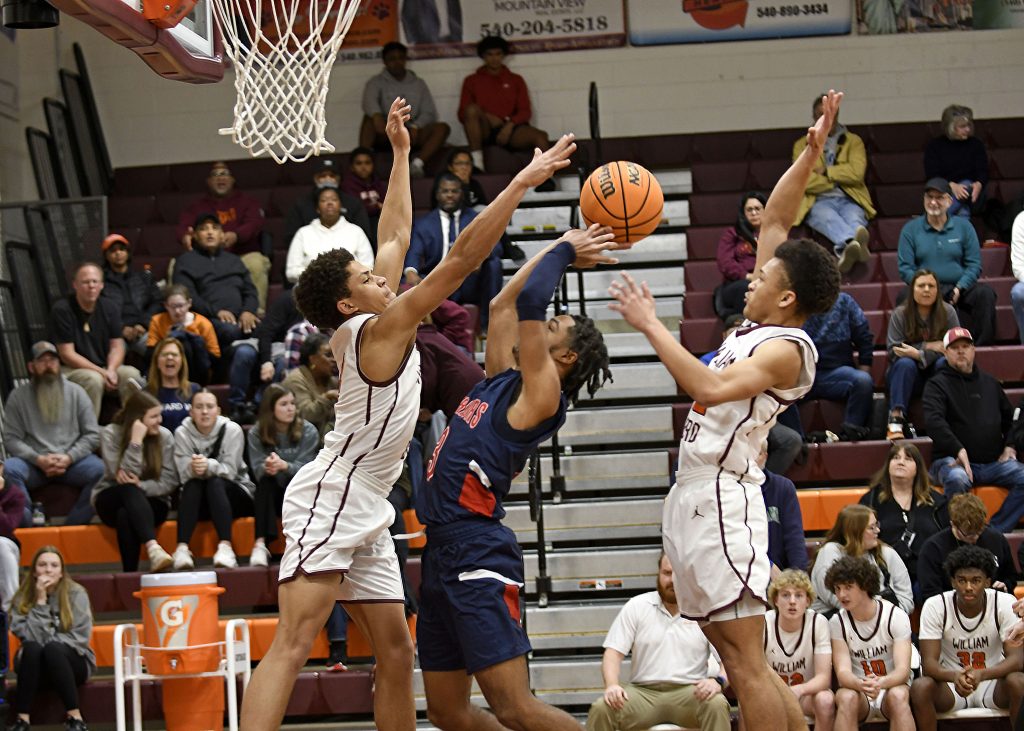 Magna Vista senior guard Bryson Kidd is sandwiched between William Byrd defenders Isiah Board (12) and Israel Hairston (4) as he drives to the hoop Friday night in Vinton.