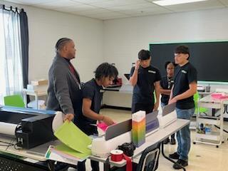 MHS business teacher Christopher Talley helps students prepare orders.