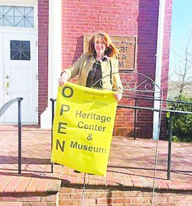 Holly Kozelsky hangs the ‘Open” sign outside the museum at 1 East Main Street in Martinsville.