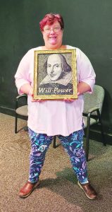 Devan Walsh poses with a painting of Shakespeare.