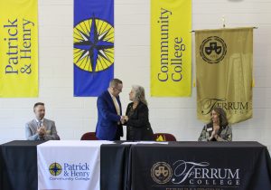 P&HCC Vice President of Academic & Student Success Services Dr. Chris Wikstrom and Ferrum Provost Dr. Delia Heck look on as P&HCC President Dr. Greg Hodges and Ferrum College President Dr. Mirta Martin shake hands at the recent signing event.