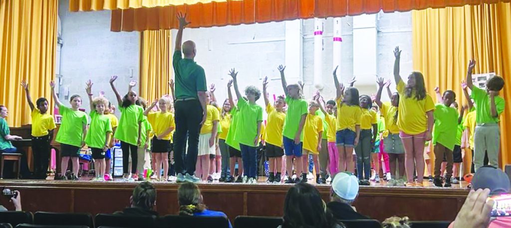 Pedro Szalay leads the G.W. Carver students through their rehearsed dance.