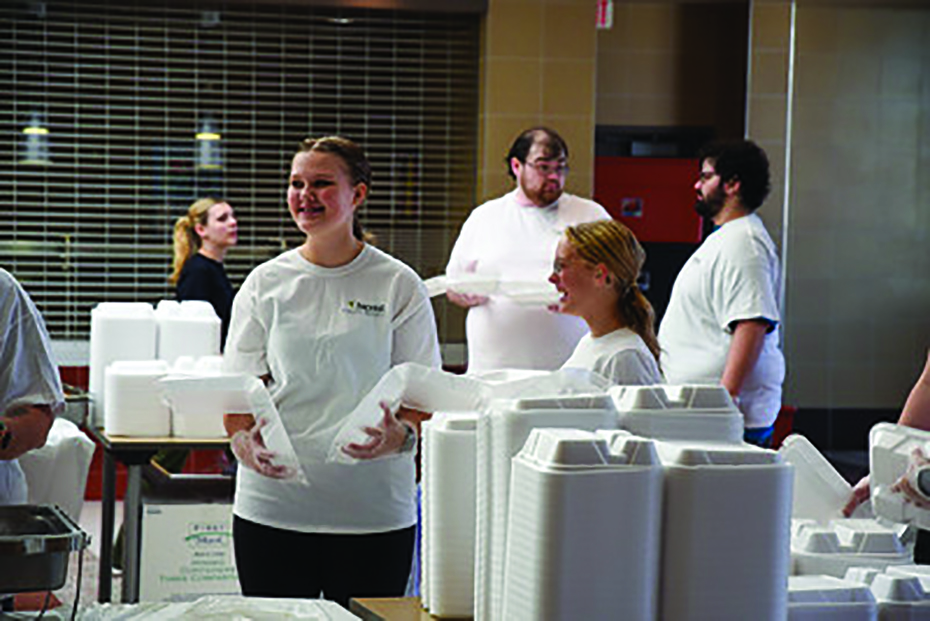 Volunteers at the 2023 dinner prepare meals with a smile, embodying the spirit of Thanksgiving.