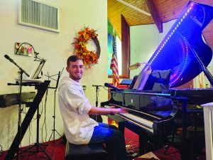 Dylan Chappell poses with the grand piano at First Assembly of God in Martinsville, Va.