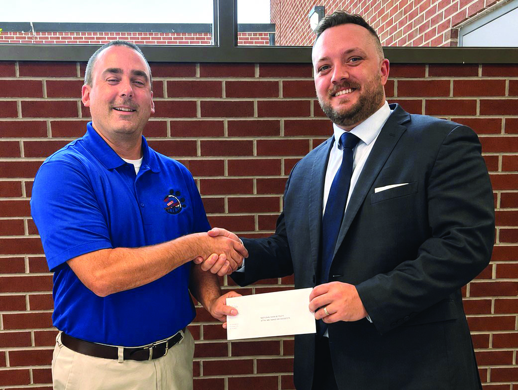 Radford High School Principal Adam Simpson (left) accepts a check from Radford High School Foundation Board Member Harri