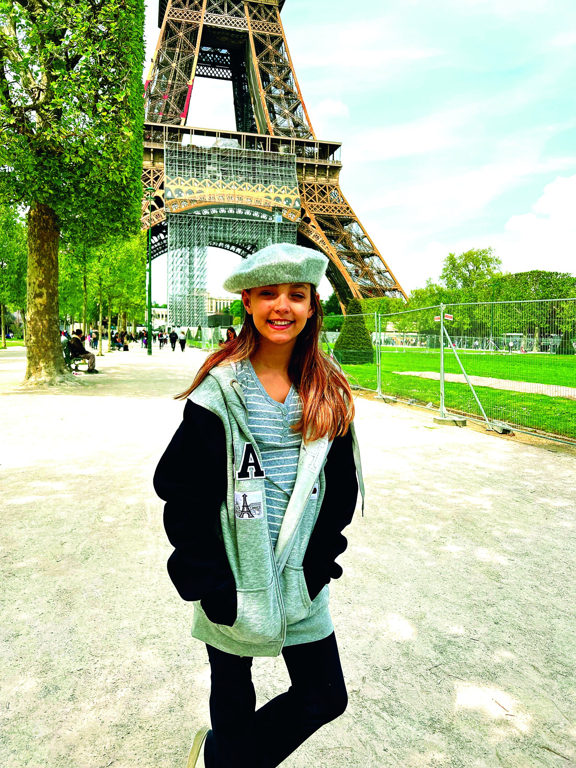 child in beret in front of eiffel tower with greenery