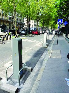 photo of grey charging station on city street with cars and trees