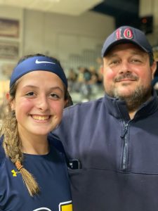 smiling daughter on left with braid and athletic uniform, new chief  with goatee and ball cap and arm around his daughter on right