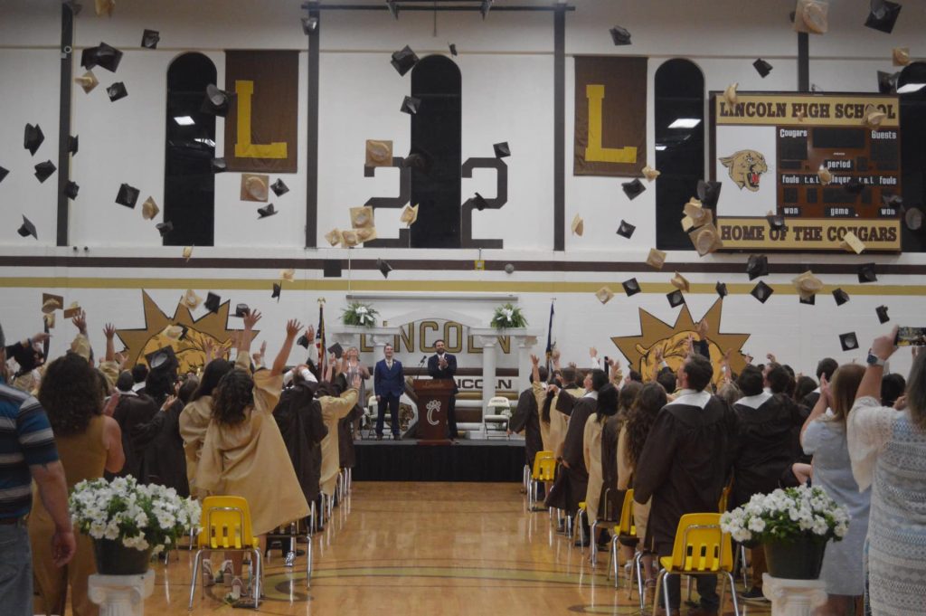 graduates throwing caps in the gymnasium