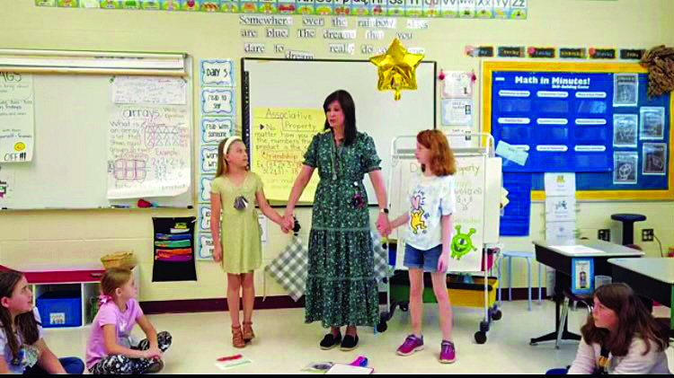 children hold hands with teacher for standing group activity