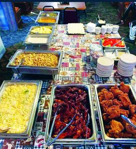 chicken, potatoes, gravy, salad on a table with a plastic tablecloth, plates and cups