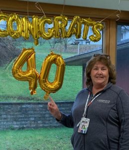 She's standing, smiling, next to a "Congrats 40" bubble letter sign in the window at the doctor's office.