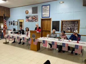 They are seated at a table with American flags displayed.