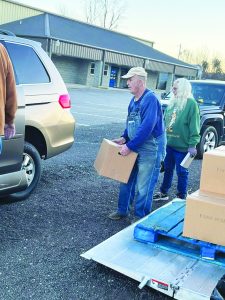 Volunteers load food boxes in the waiting vehicles of the drive-thru line on distribution days. 