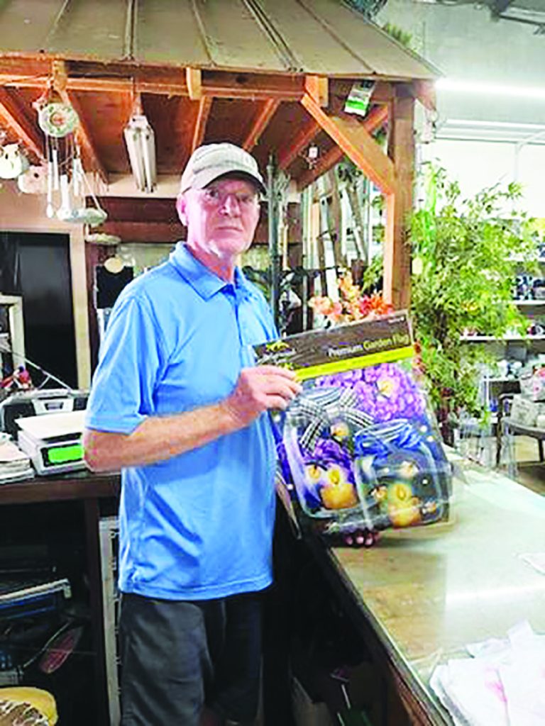 Garden flags, like the one Stanley Fain is holding, and tons of outdoor and indoor décor await customers visiting All Seasons. Most of the inventory is on sale, with a few exceptions.