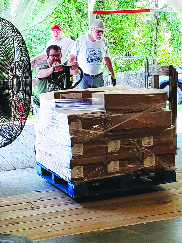 Volunteers work in a conveyor belt system to pack the food boxes and prepare them for distribution.