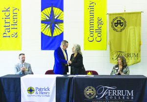 P&HCC Vice President of Academic & Student Success Services Dr. Chris Wikstrom and Ferrum Provost Dr. Delia Heck look on as P&HCC President Dr. Greg Hodges and Ferrum College President Dr. Mirta Martin shake hands at the recent signing event.