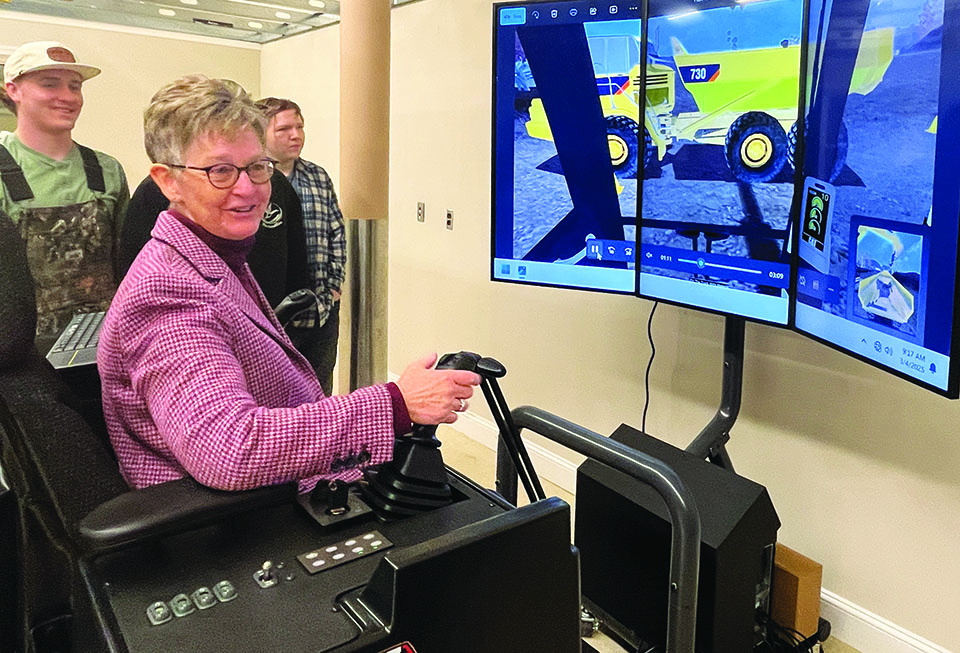 Phillip E. and Carole R. Ratcliffe Foundation CEO Carlene Cassidy tests the CAT simulator as HEO students observe.