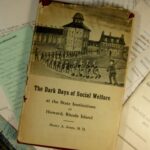 Photo of the Book "The Dark Days of Social Welfare..." with a battered dust jacket atop several papers.