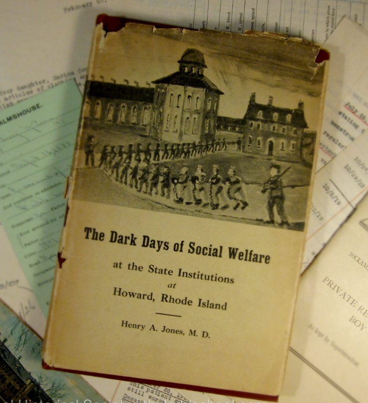 Photo of the Book "The Dark Days of Social Welfare..." with a battered dust jacket atop several papers.