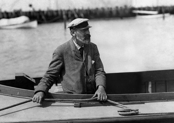 black and white photo of an elderly white man, identified at Nathanael Herreshoff, in a boat.