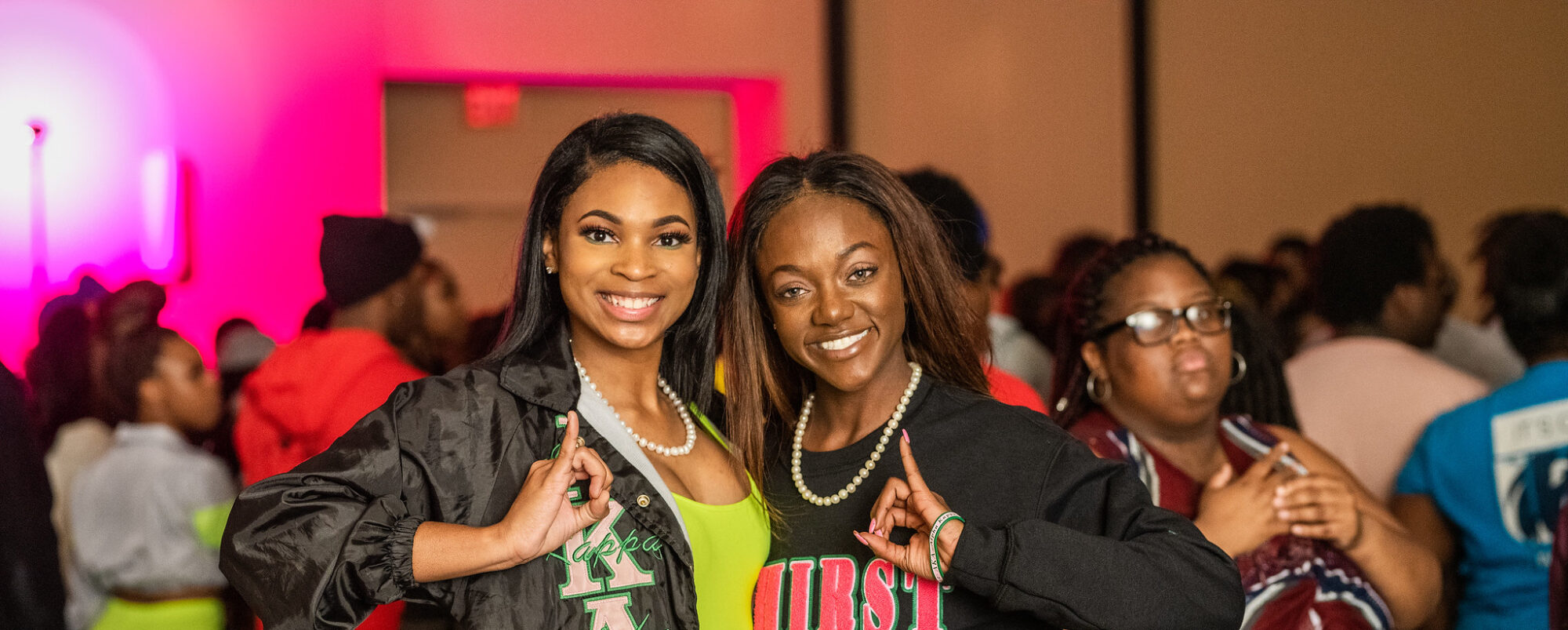 Two sorority members showing their sorority's hand gestures.