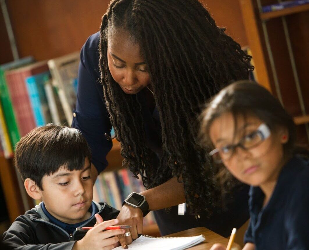 Woman tutoring two children.