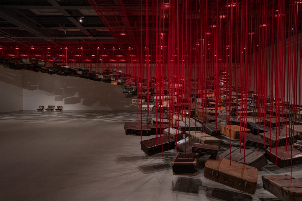 塩田千春，《集聚—找尋目的地》，2014/2021， 行李箱、馬達、紅繩，尺寸依空間而定