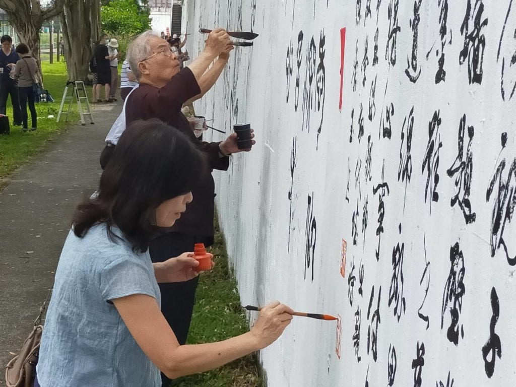 陳秀玉理事長（前）與沈榮槐會長相繼在牆面做壁書撰寫。（記者 辛澎祥/攝）