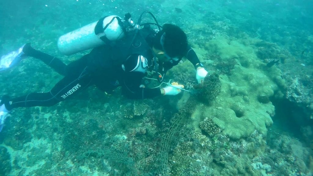 漁民潛入海底清理漁網勾住的漁具。