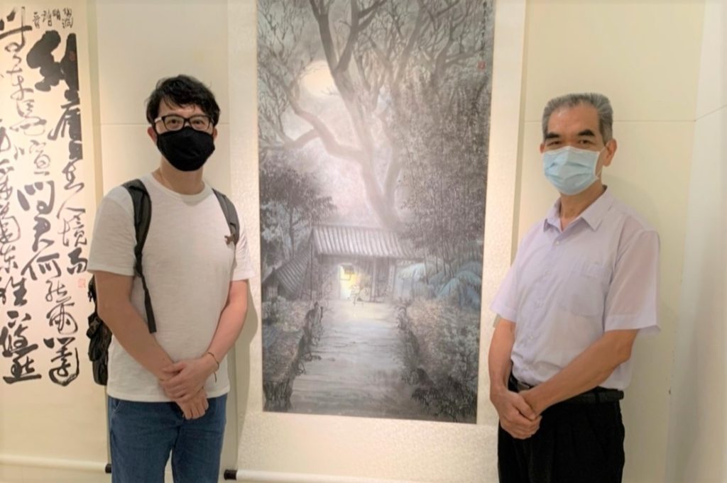 ▲陳金海老師（右）與他的學生劉瑛峯展場合影，後為劉瑛峯作品「夜色」。（記者 辛澎祥/攝）