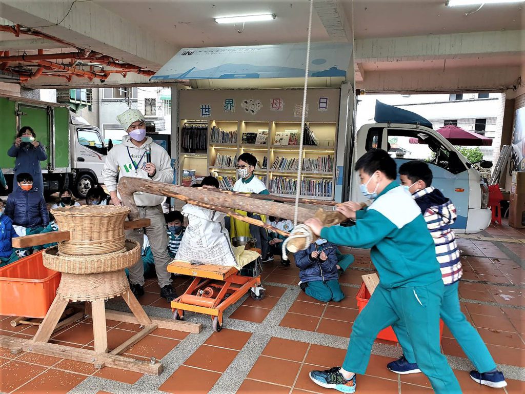 新北市立圖書館行動圖書車特別帶著古早碾米機，同時邀請土礱師賴咏華到淡水國小，讓小朋友體驗傳統的爆米香技藝，同時學臺語。〈新北市圖提供〉