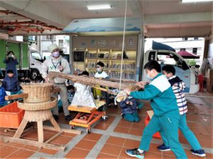 新北市立圖書館行動圖書車特別帶著古早碾米機，同時邀請土礱師賴咏華到淡水國小，讓小朋友體驗傳統的爆米香技藝，同時學臺語。〈新北市圖提供〉