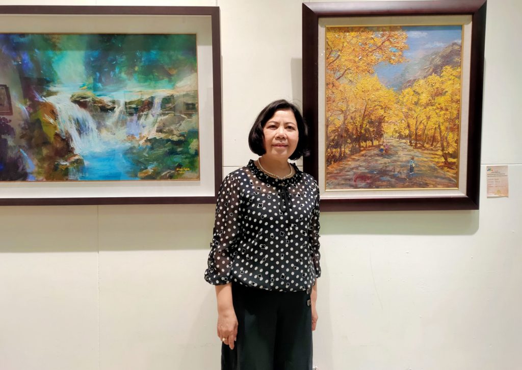 吳淑英老師在她的作品前留下永恒。(記者 辛澎祥/攝)