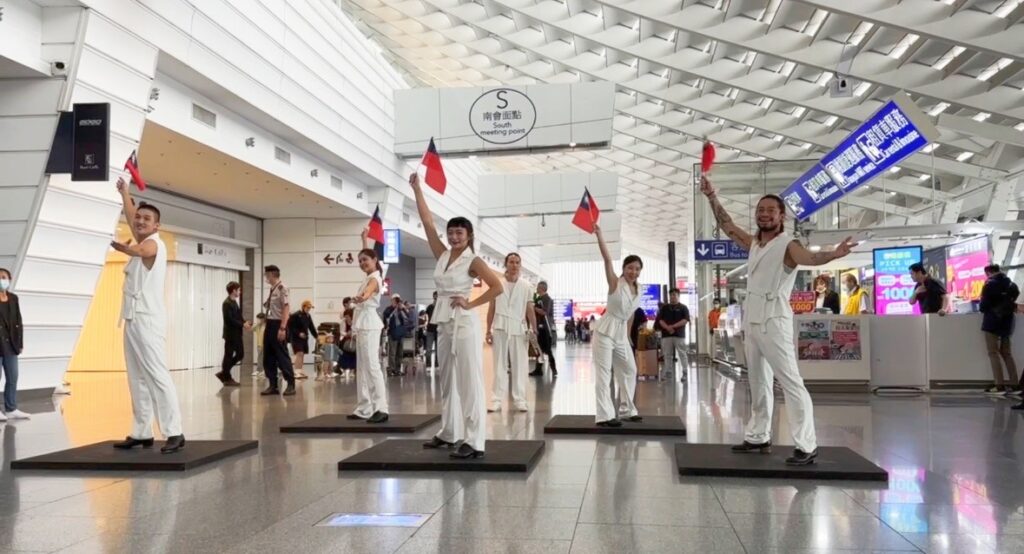 桃園國際機場飄揚輕快音樂與舞蹈，一群踢踏舞者和銅管樂手，揮舞國旗在航廈大廳快閃演出，一起慶祝雙十國慶。