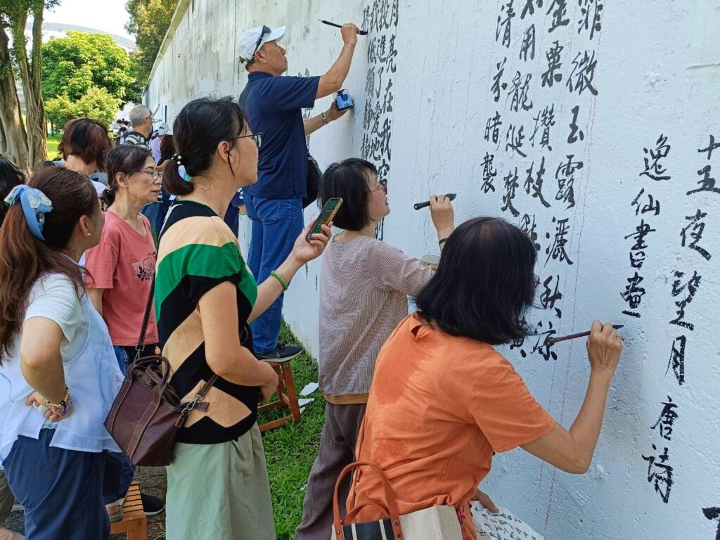 ▲知名女書法家也是書會領導人的連瑞芬老師（右二）專注壁書書寫，受到多人的圍觀駐足欣賞。（記者 辛澎祥/攝）