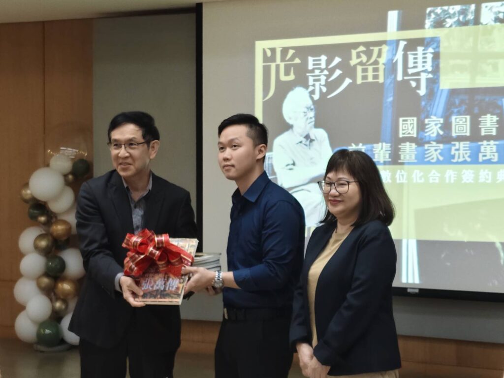 張萬傳家屬黃秋菊女士(右)及張民立先生(中)致贈國圖的張萬傳主題圖書,由翁誌聰副館長代表接受。(記者 陳安婷/攝)