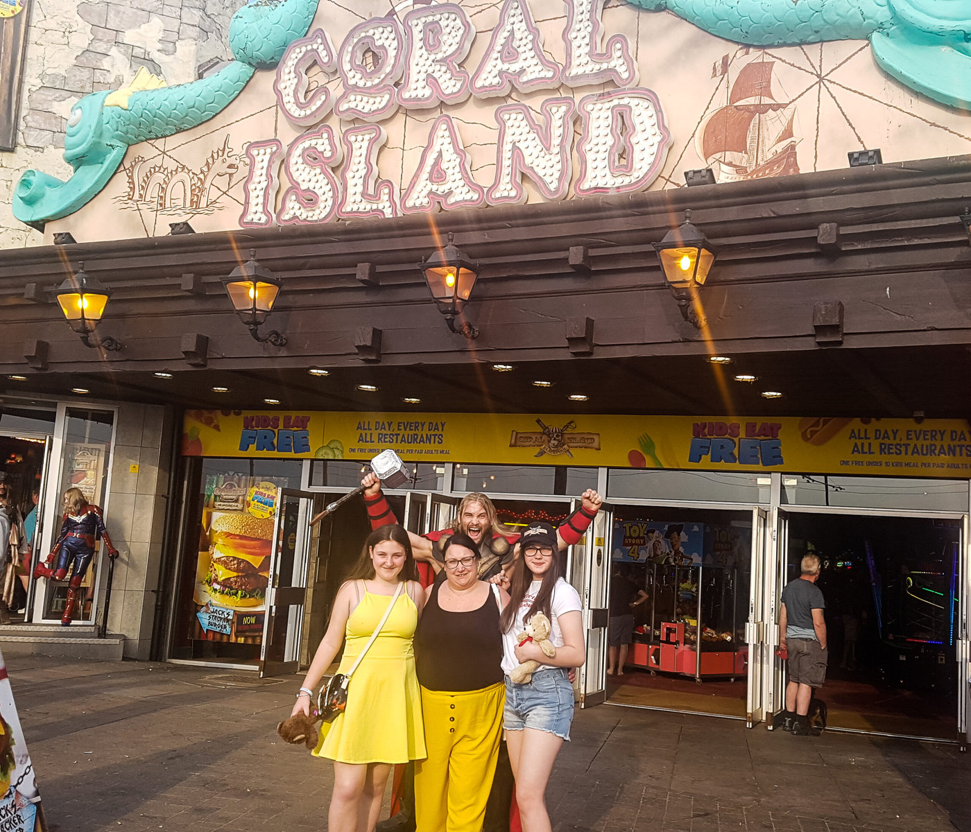 three women stading outside coral island blackpool with a man in a thor costume behind them