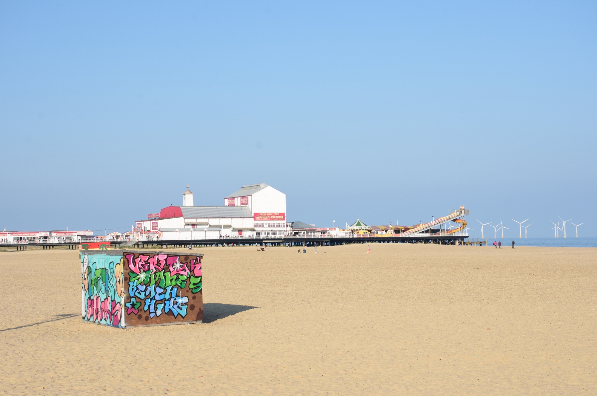 view of great yarmouth beach with the pier in view and a deckchair hut