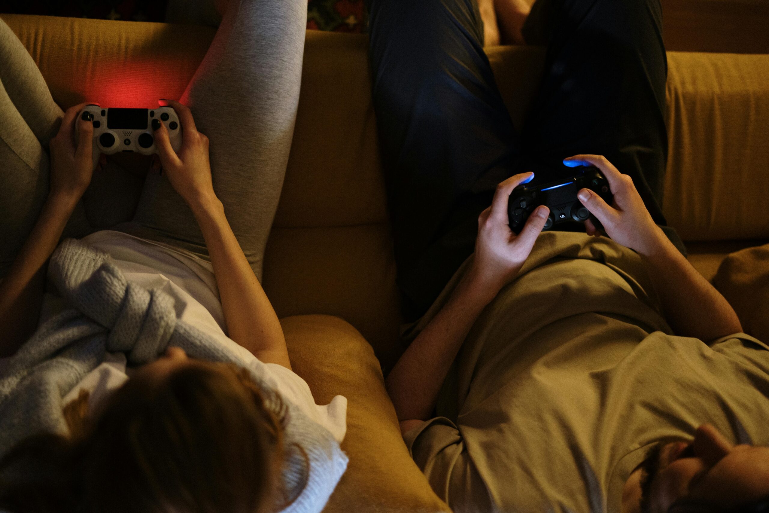 two people lying down holding video game controllers