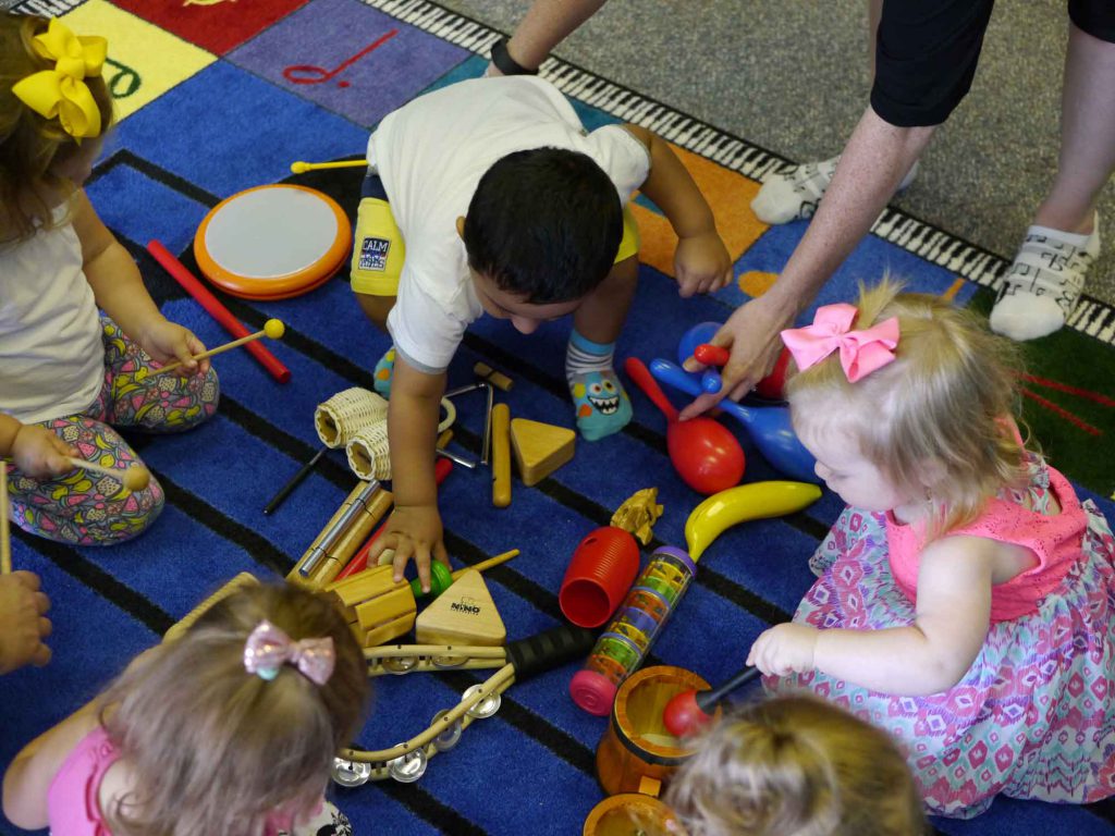 Toddlers playing with instruments in music class, listening to one of the 10 Free Songs in our download