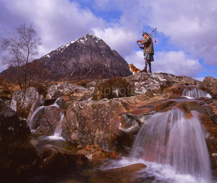 A Dramatic View Of Buchaille Etive Mhor With A Piper Playing A Haunting Melody West Highlands