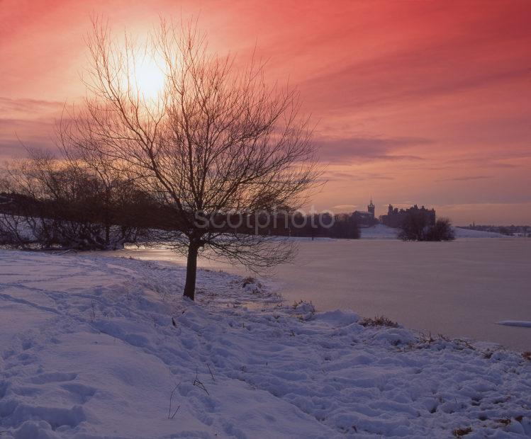 Winter Sunset From The Frozen Shore Of Linlithgow Loch With Distant Linlithgow Palace West Lothian