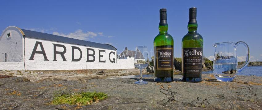 Ardbeg Distillery With Bottles Of Whiskey On Rocks