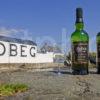 Ardbeg Distillery With Bottles Of Whiskey On Rocks